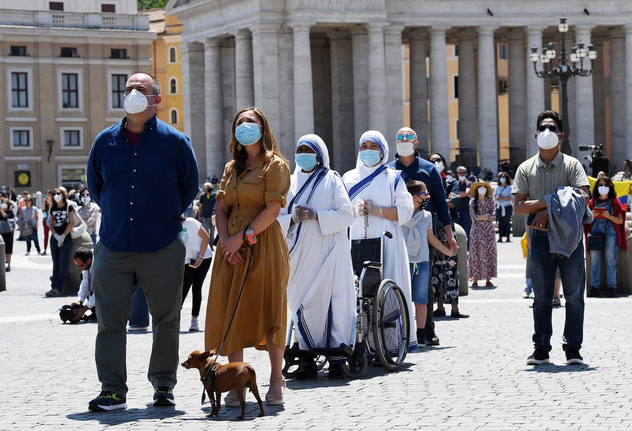 Religious and pilgrims, wearing protective face masks, gather in St. Peter Square at the Vatican on May 31, 2020.