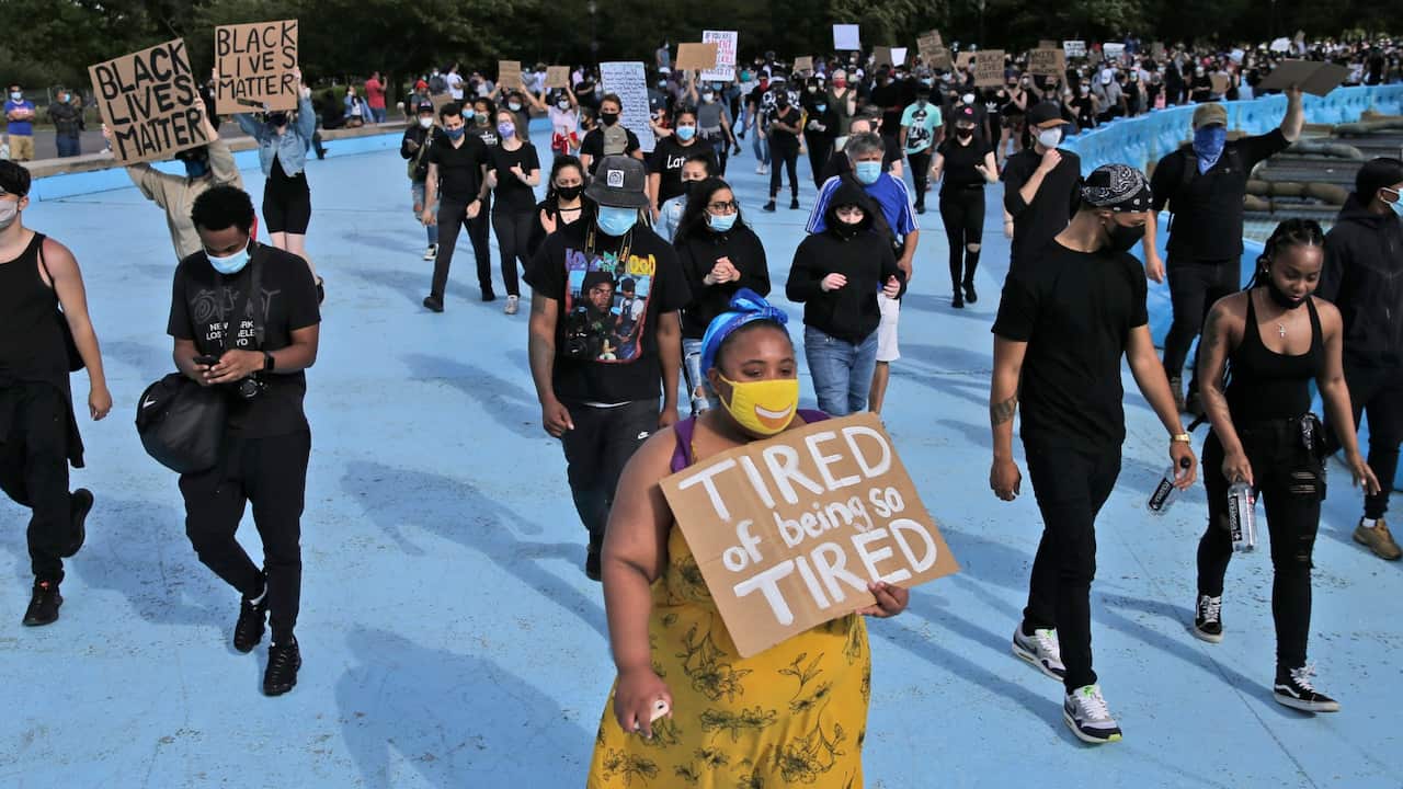Protesters march around large sculpture of a globe in Flushing Meadows Corona Park in the Queens borough of New York, Sunday, May 31, 2020.