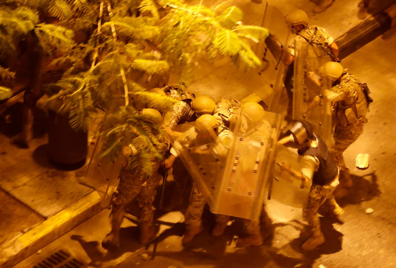 Lebanese army soldiers cover themselves as they step back after the anti-government protesters storm them by stones