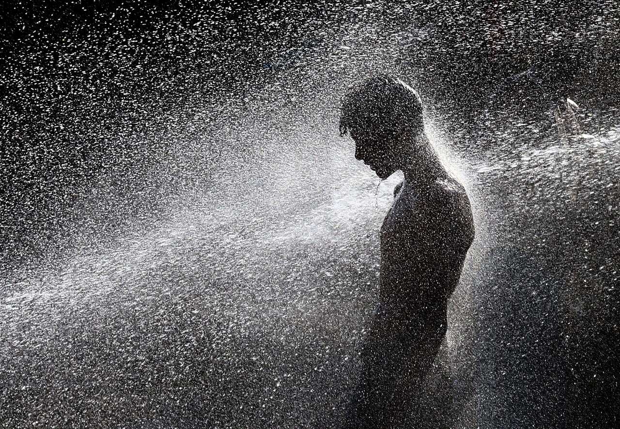 epaselect epa08523016 People cool off at a punctured water supply line on a road as a heatwave continues in Karachi, Pakistan, 02 July 2020.  EPA/SHAHZAIB AKBER
