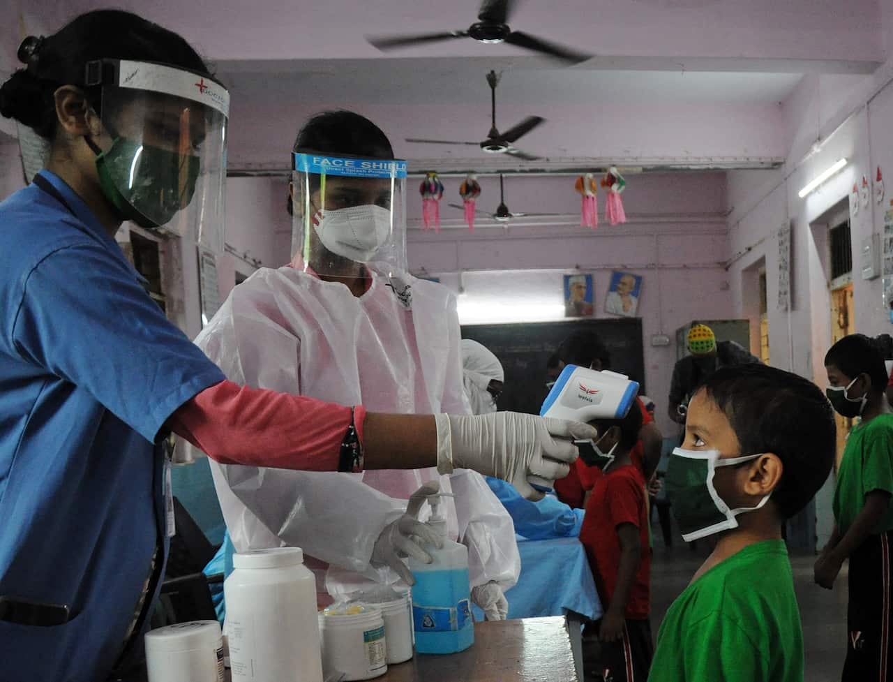 A health worker checks the body temperature of a kid at a children's home.