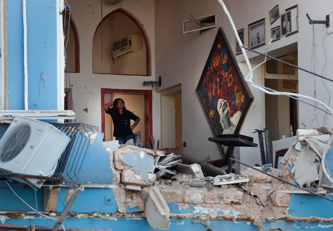 A woman stands inside a damaged restaurant a day after an explosion hit the seaport of Beirut, Lebanon, Wednesday, Aug. 5, 2020. (AP Photo/Hussein Malla)