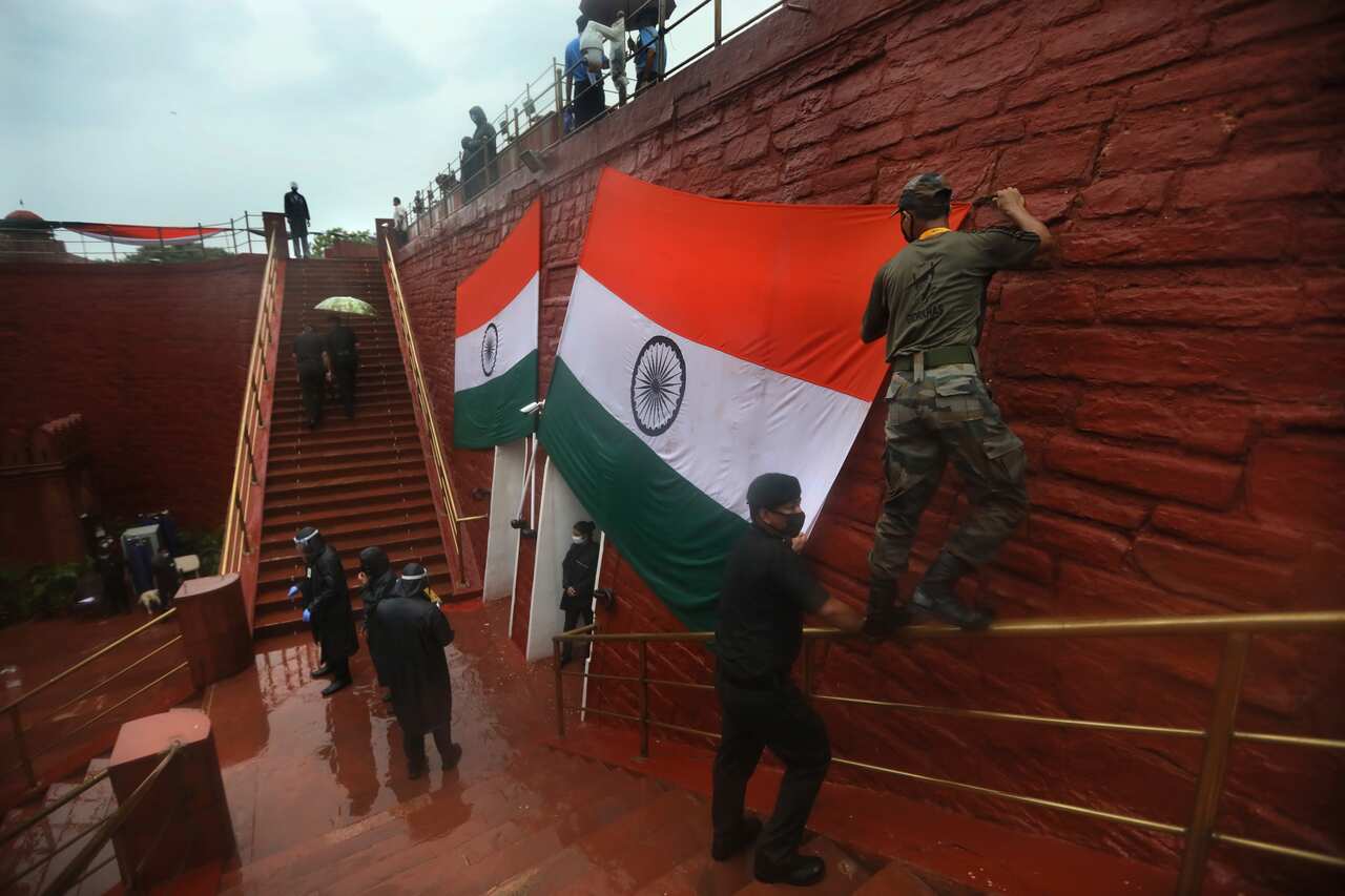 Indian army soldiers adjust the national flag on display during a full dress rehearsals of the Independence Day ceremony on the rampart of Red fort.
