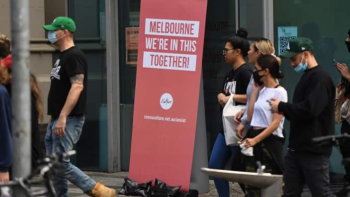 Protesters walk past a sign during an anti-lockdown protest in Melbourne, Sunday, September 13, 2020. 