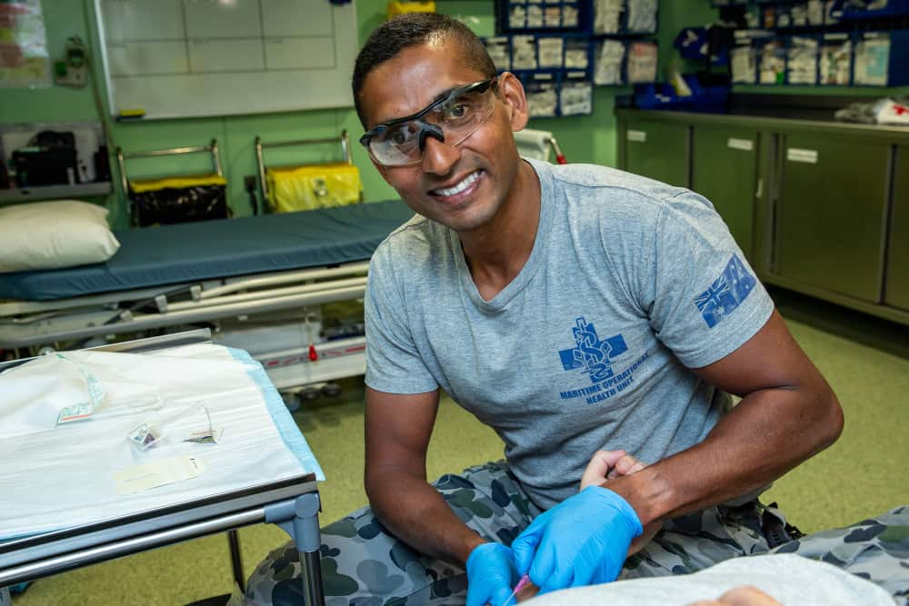 Royal Australian Navy Nursing Officer Lieutenant Commander Roneeel Chandra prepares to treat a patient onboard HMAS Adelaide during Exercise Sea Wader.