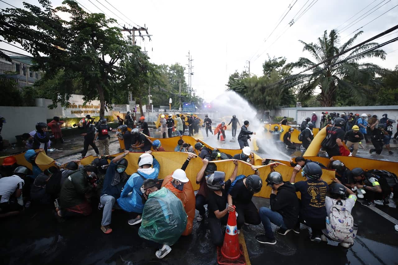 Pro-democracy protesters take cover as police fire tear gas and water cannon at a demonstration against a charter amendment at Parliament Bangkok, 17 Nov 2020. 