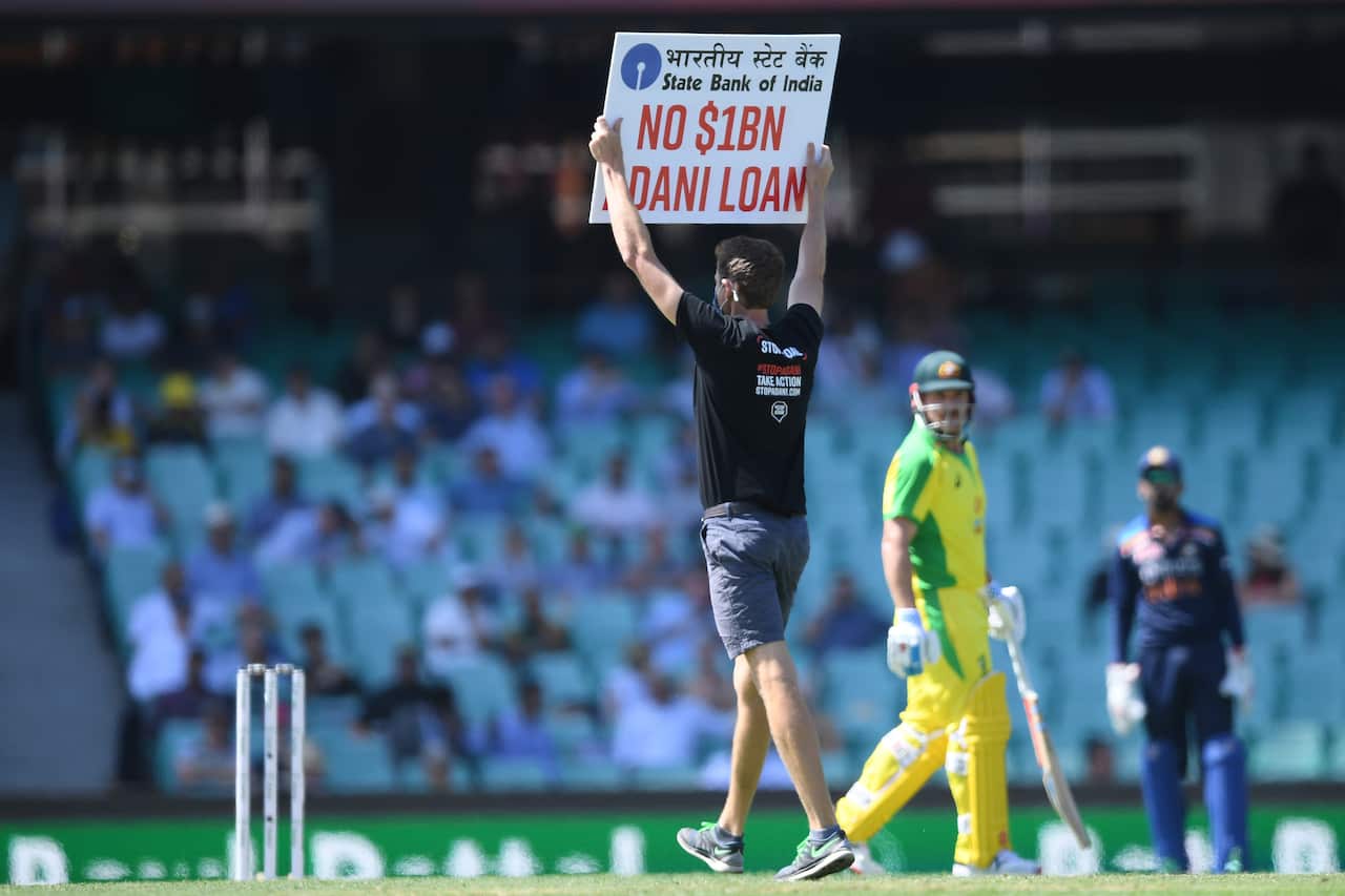 Aaron Finch of Australia looks on as a pitch invader protesting against the Adani Coal Mine stands in the middle of the SCG during the first ODI cricket match.
