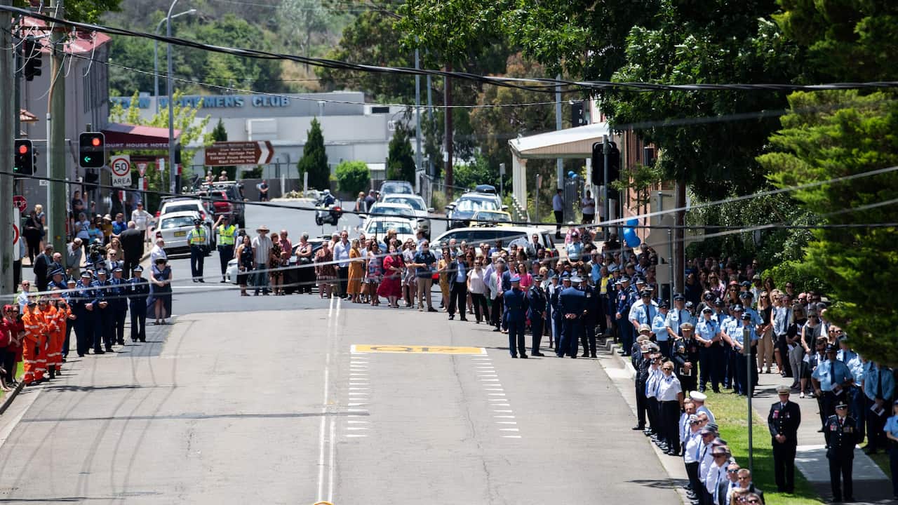 People are seen lining the street as the hearse proceeds through the town at the conclusion of the police funeral of Senior Constable Kelly Foster