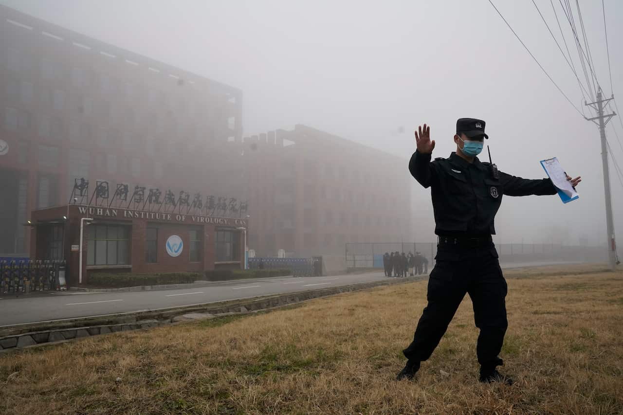 A security personnel moves journalists away from the Wuhan Institute of Virology after a World Health Organization team arrives