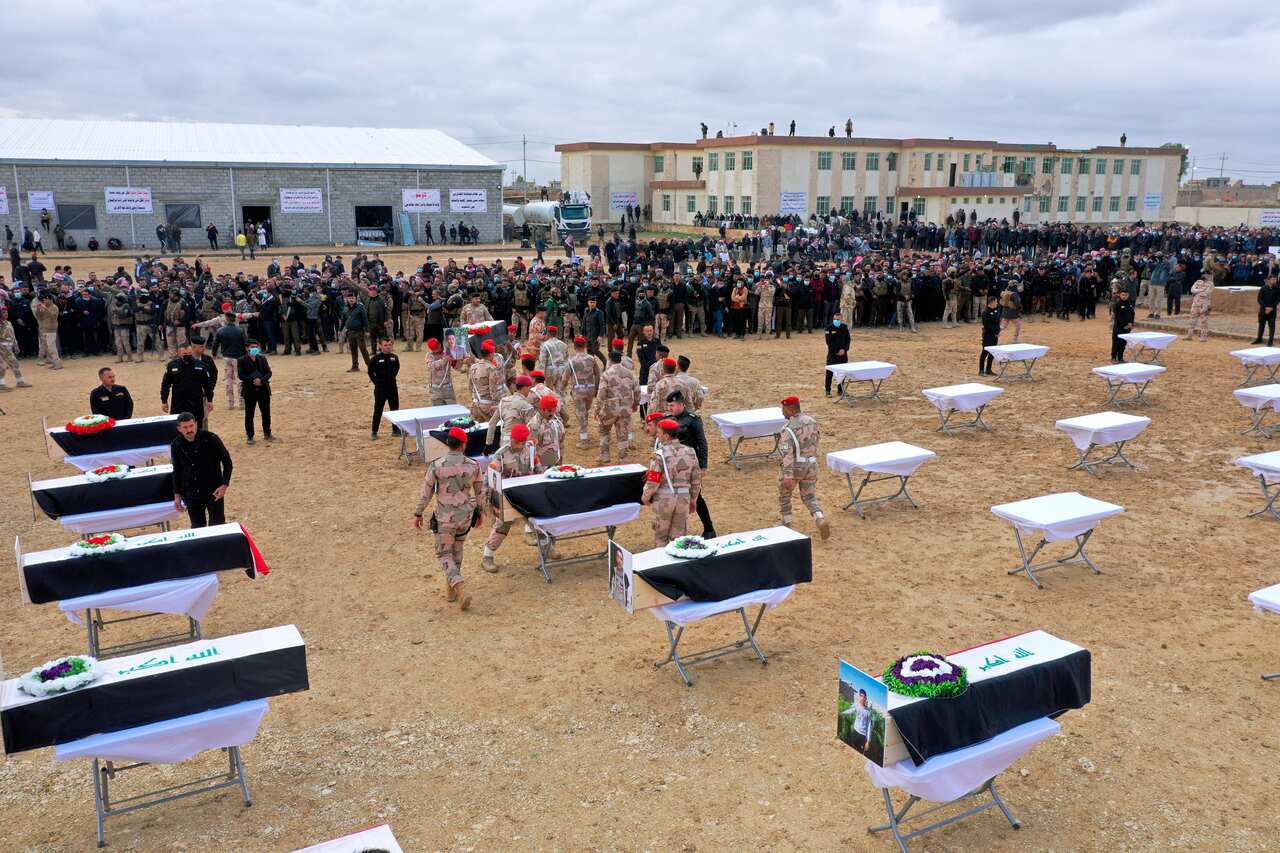 Mourners prepare to buried the remains of Yazidi victims in a cemetery in Sinjar, Iraq, Saturday, Feb. 6, 2021.
