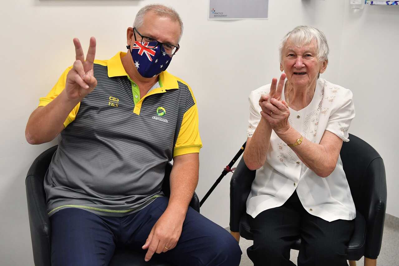 Australian Prime Minister Scott Morrison gestures alongside Aged care resident Jane Malysiak (left) as she receives her second COVID-19 vaccination.