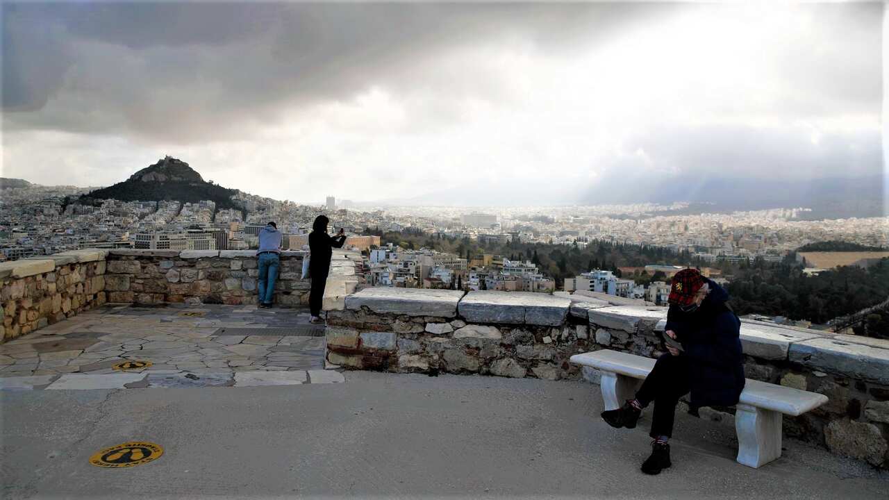 The first visitors wearing face masks to protect against the spread of coronavirus, take photographs atop of Lycabettus hill in Athens. 