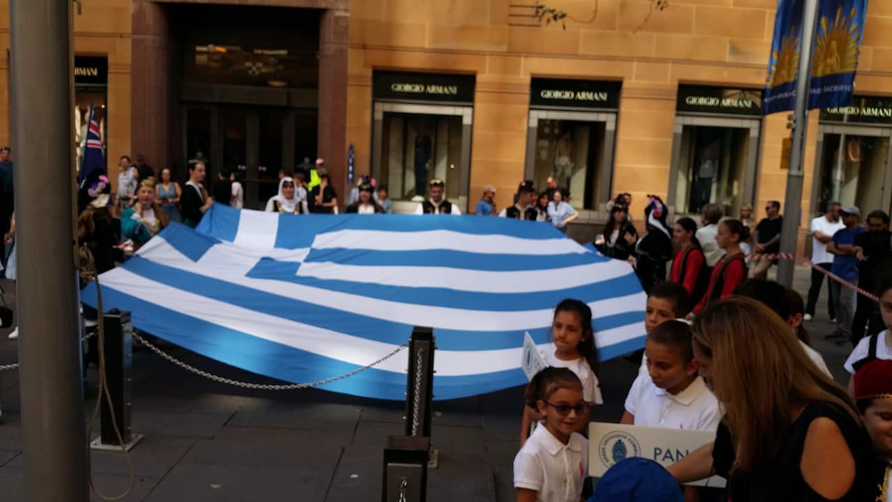 Μαθητές και μαθήτριες κρατουν απλωμένη την ελληνική σημαία