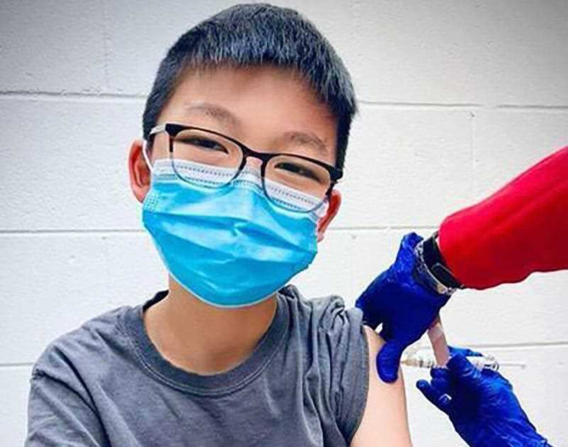 In this Dec. 22, 2020, photo, provided by Richard Chung, his son Caleb Chung receives the first dose of Pfizer coronavirus vaccine or placebo as a trial participant for kids ages 12-15, at Duke University Health System in Durham, N.C.