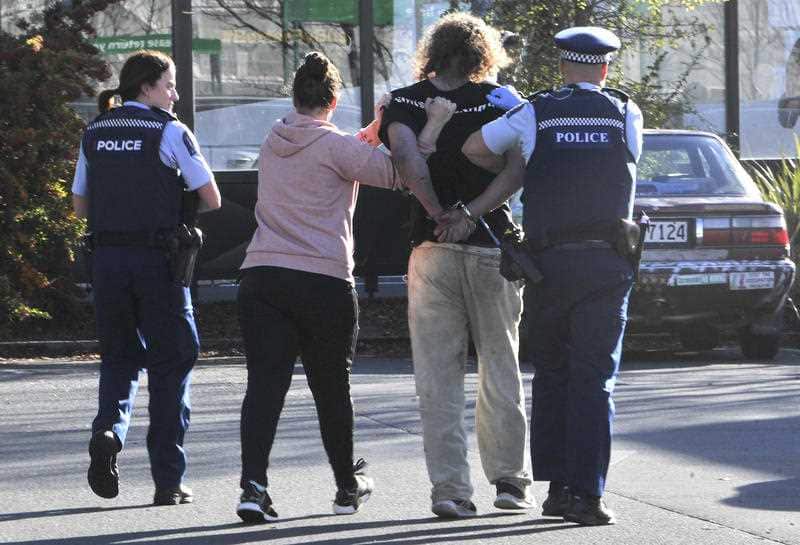 Police take a suspect into custody near the Countdown supermarket in central Dunedin, New Zealand, Monday, May 10, 2021. 