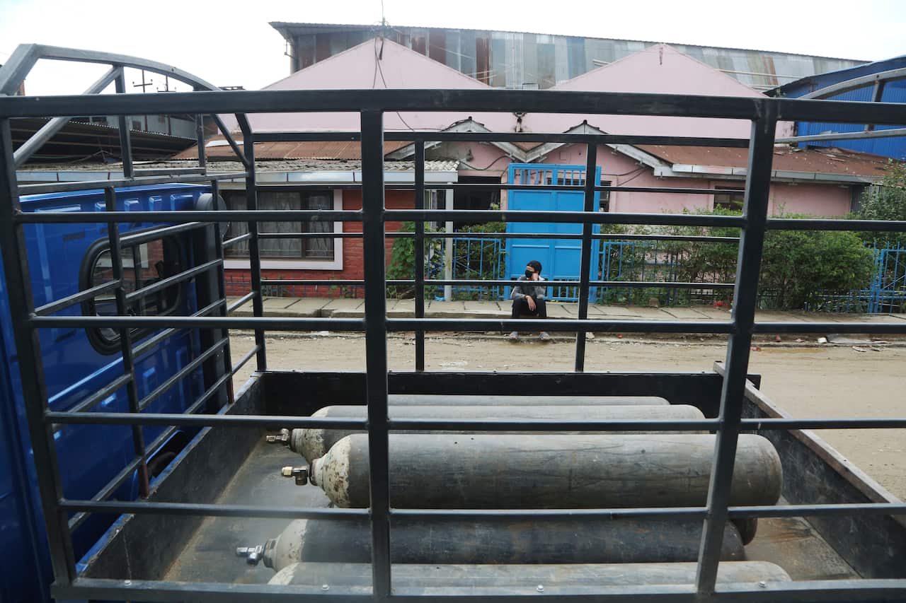 A Nepali man waits to refill medical oxygen cylinders at an oxygen plant in Kathmandu, Nepal, 