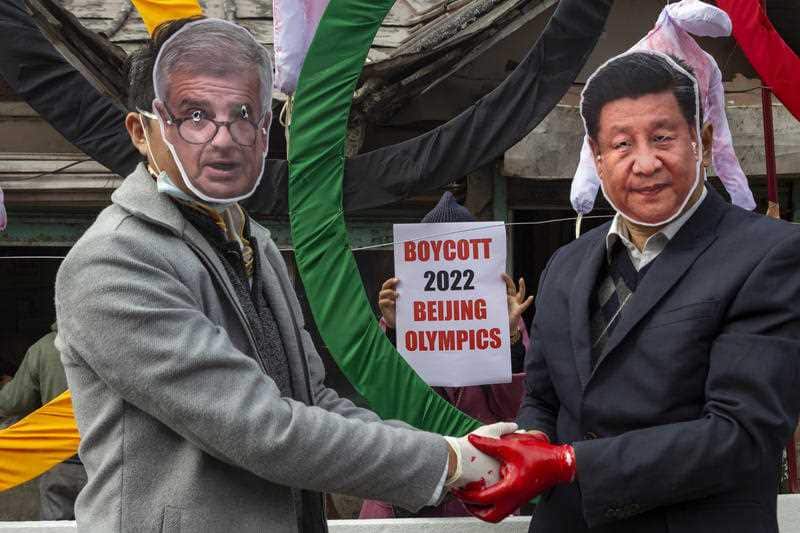 Activists wearing masks of IOC President Thomas Bach, left, and Chinese President Xi Jinping pose in front of the Olympic Rings during a street protest against the holding of the 2022 Beijing Winter Olympics, in Dharmsala, India.