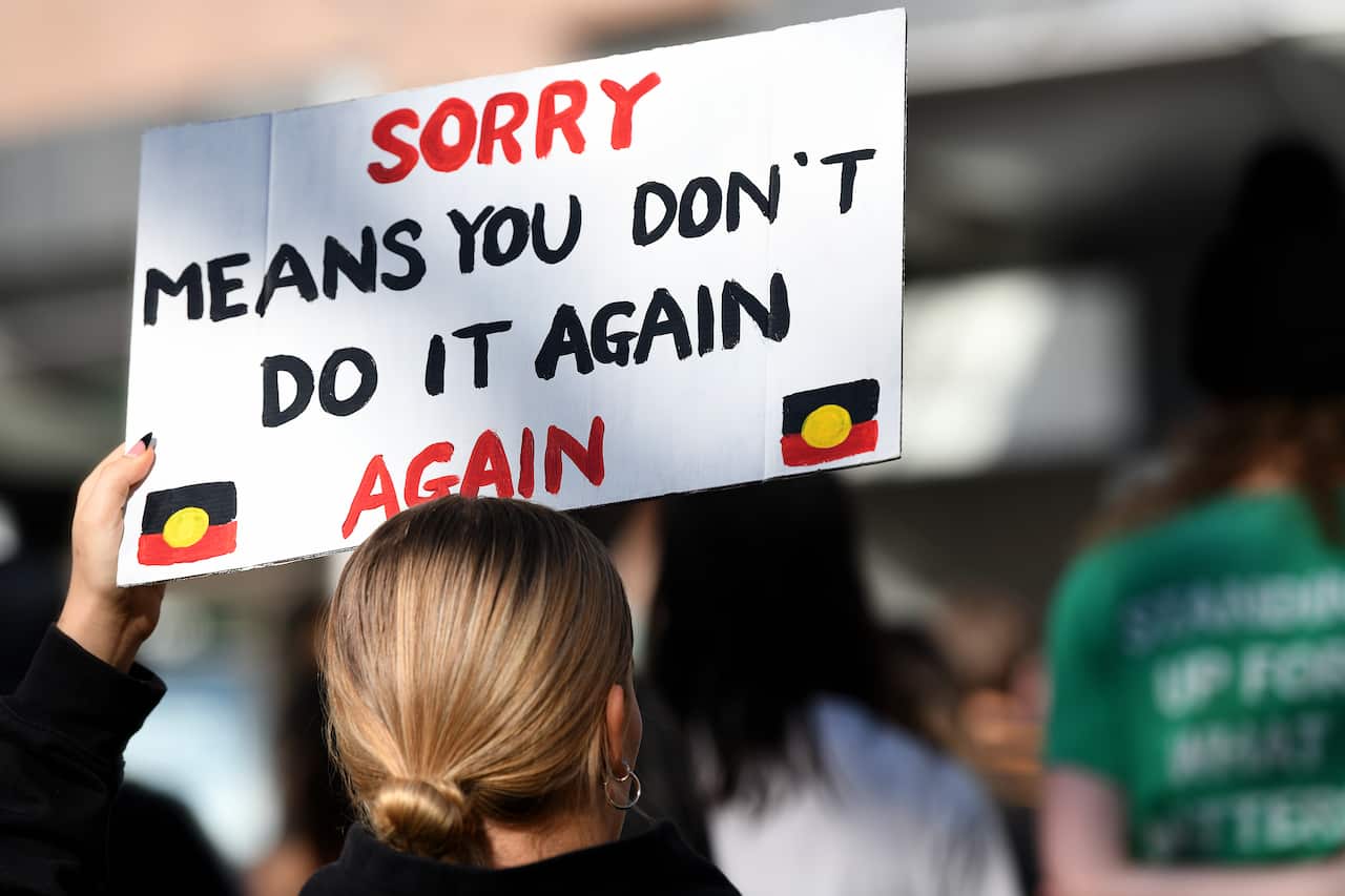 Protestors hold placards as they march through the CBD during a Stop The Stolen Generation! Sorry Day Rally, Sydney, Wednesday, May 26, 2021. (AAP Image/Bianca De Marchi) NO ARCHIVING