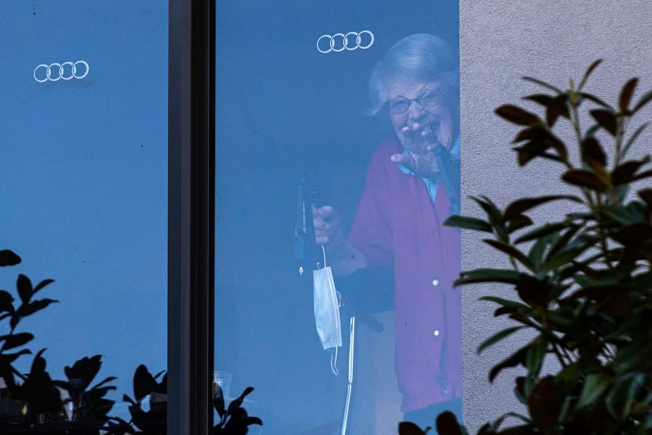 A resident at the Arcare Aged Care facility in Maidstone reacts to media from her window, in Melbourne, Monday, May 31, 2021. (AAP Image/Daniel Pockett) NO ARCHIVING