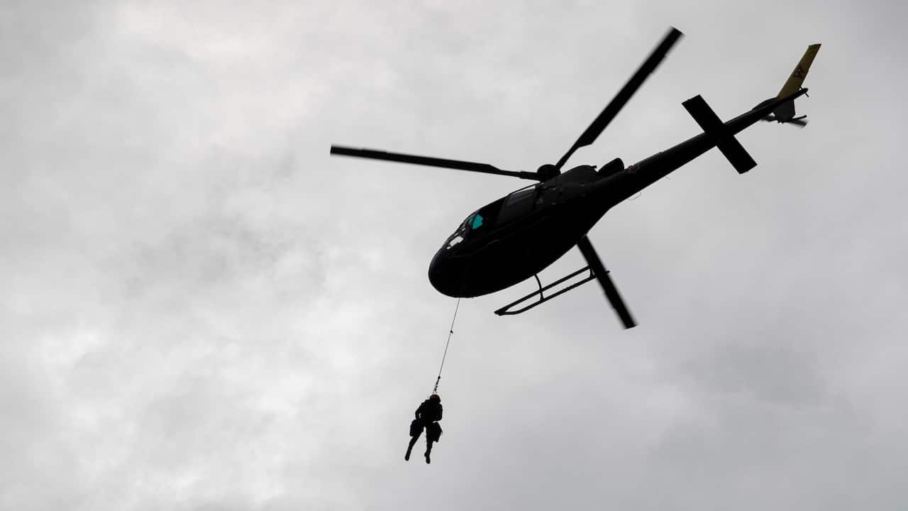 A member of the Nepali Army hangs from a helicopter to rescue stranded people in Melamchi, Sindhupalchwok district, Nepal, 16 June 2021.