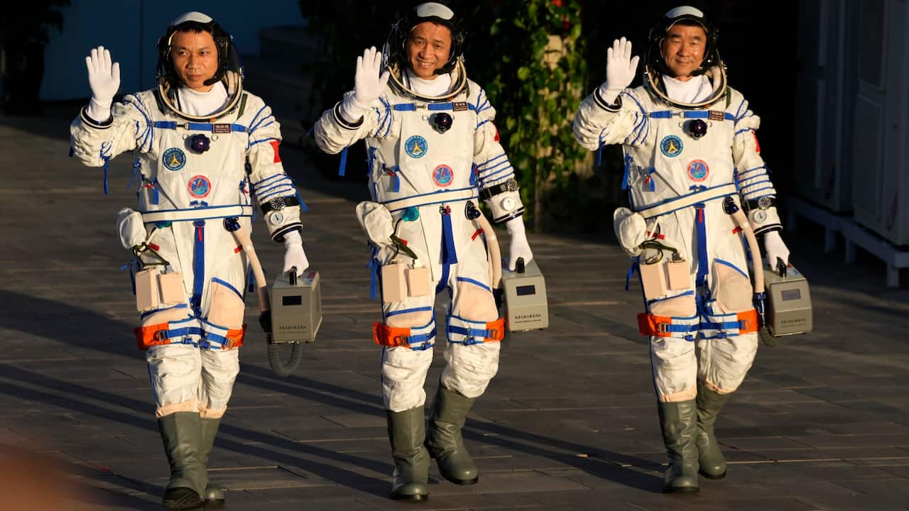 Chinese astronauts, from left, Tang Hongbo, Nie Haisheng, and Liu Boming wave as they prepare to board for liftoff