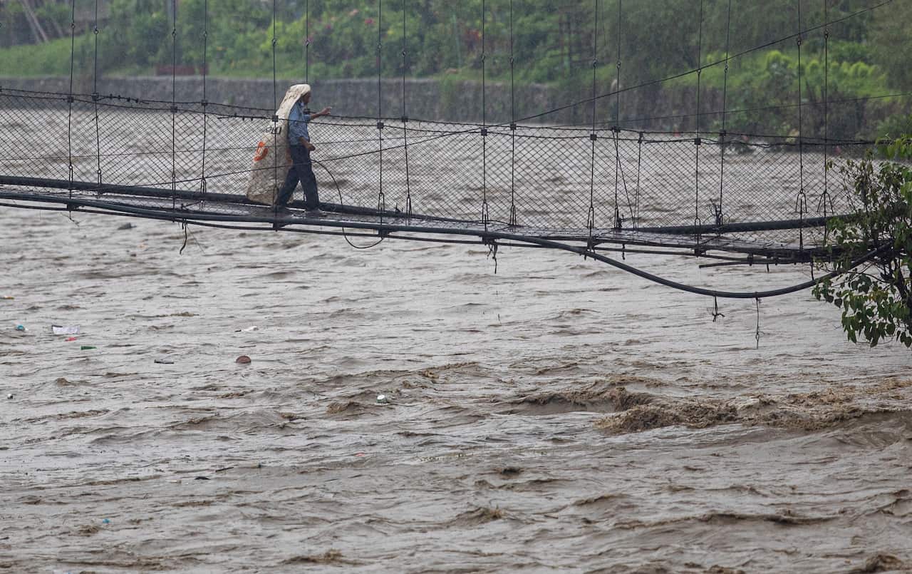 A Person walks under an umbrella as he crosses the suspension bridge over the Bishnumati River during the heavy rainfall in Kathmandu, Nepal, 01 July 2021.