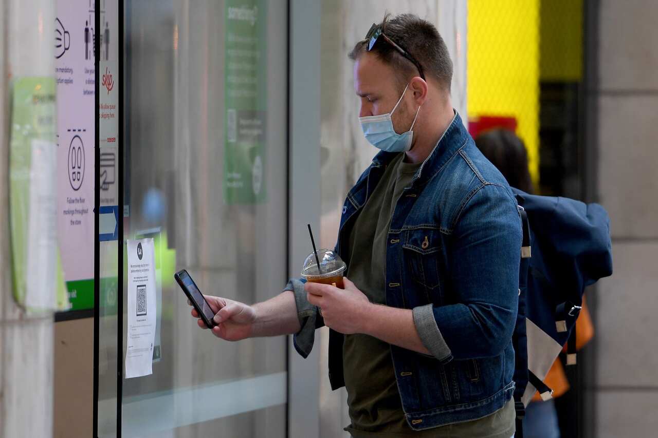 A person uses a smart phone to check-in with a QR code at a supermarket in Pitt Street mall, in Sydney