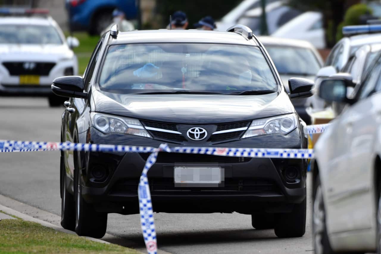 Family members of the woman who died of Covid, are directed to sit in their car by police and health workers at Green Valley in Sydney