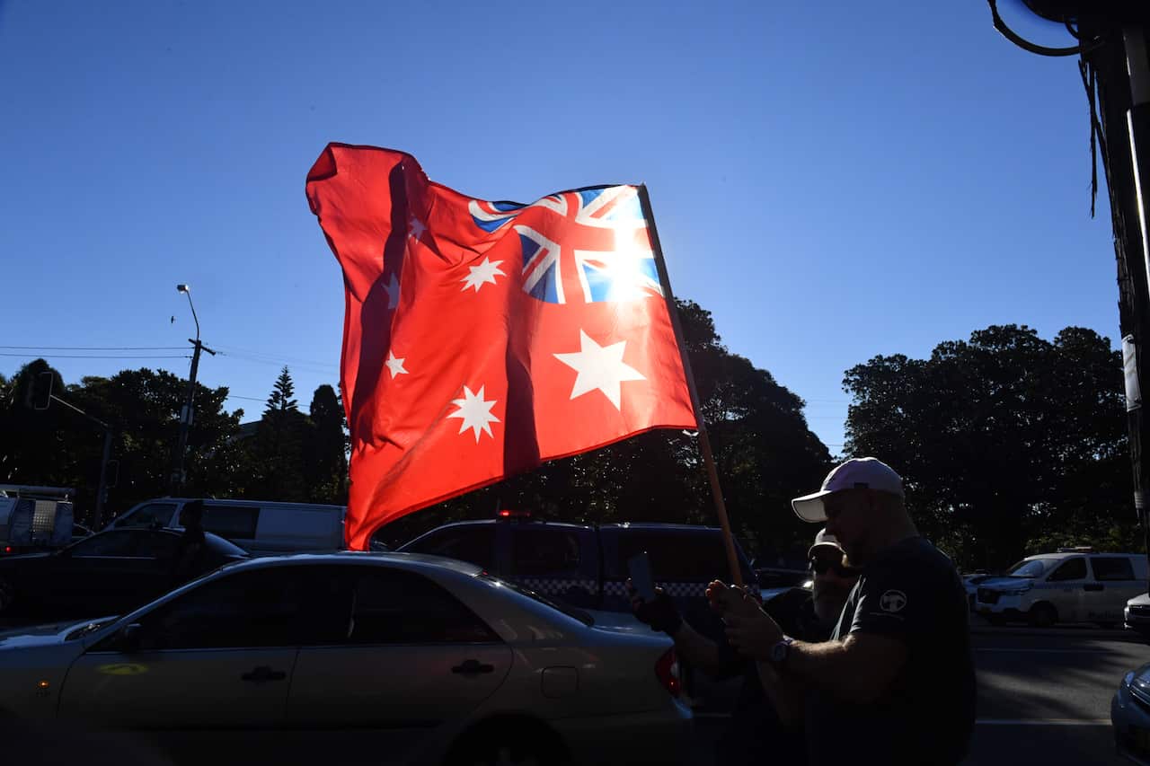 A protester waves the Australian Red Ensign flag at Victoria Park in Glebe during the ‘World Wide Rally For Freedom’ anti-lockdown rally at Hyde Park in Sydney, Saturday, July 24, 2021. (AAP Image/Mick Tsikas) NO ARCHIVING