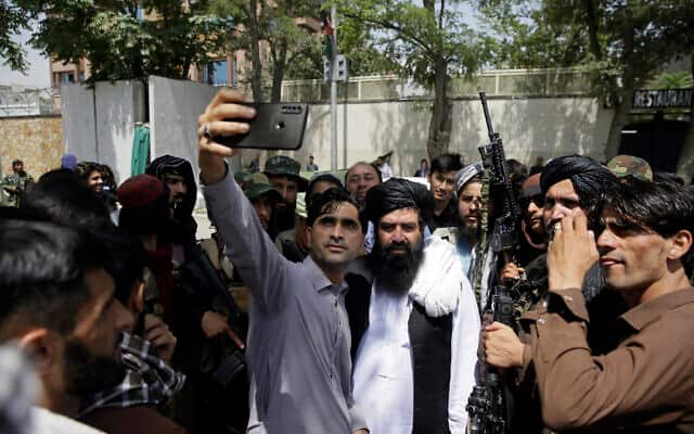 Afghans take selfie with Taliban fighters during patrol in the city of Kabul. 