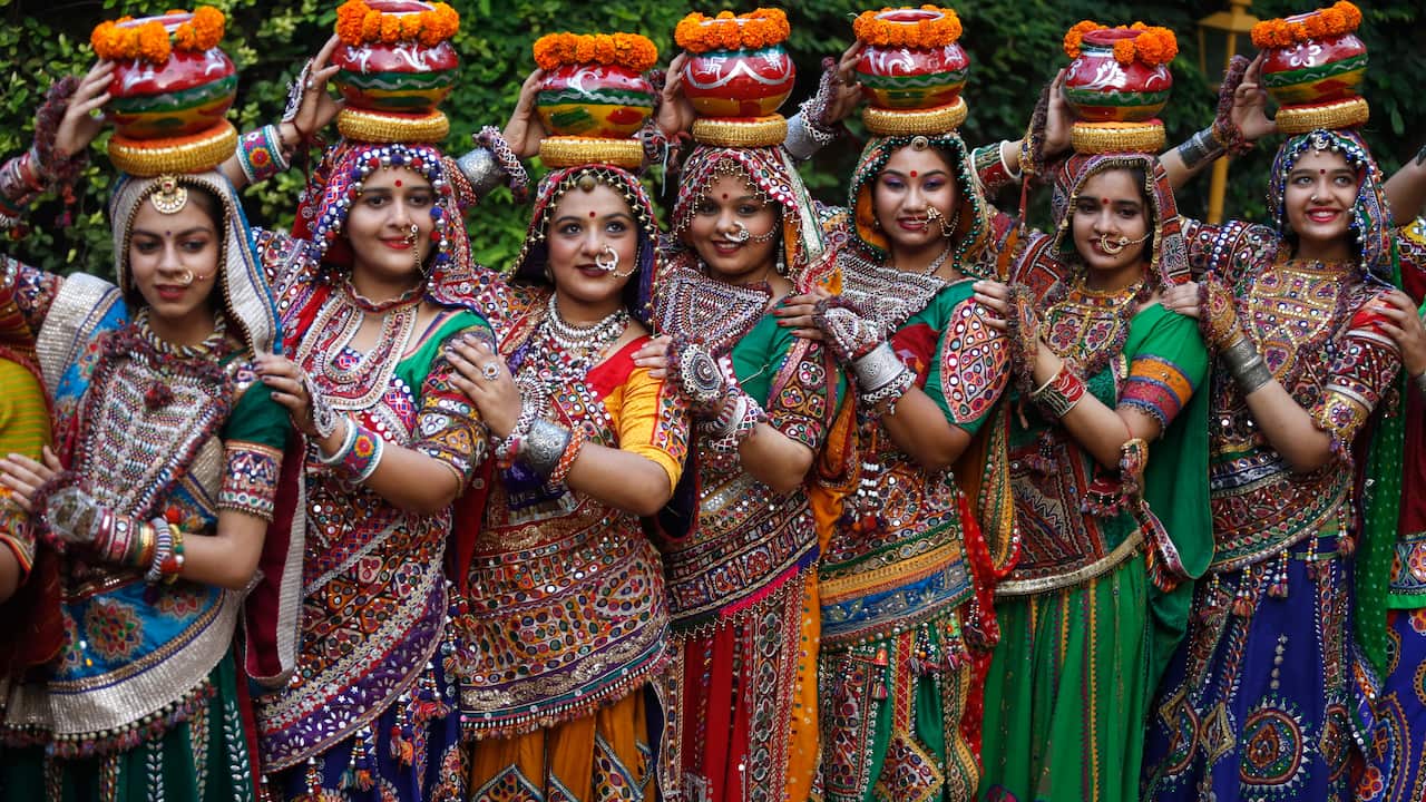Indian women in traditional attire pose for photographs before practicing Garba.