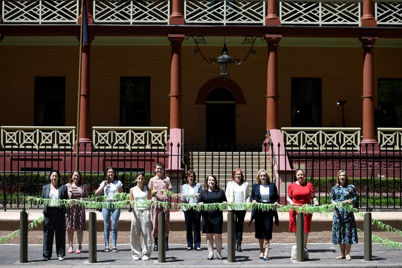 NSW Greens MP Jenny Leong (left) along with fellow MPs Felicity Wilson, Julia Finn and volunteers hang ribbons outside New South Wales Parliament House in Sydney, Thursday, October 21, 2021. Women will be hanging 6,000 ribbons outside the NSW Parliament a