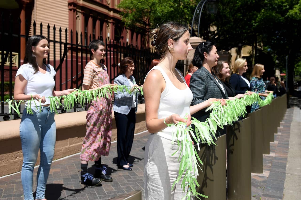 NSW Greens MP Jenny Leong (centre, right) along with co founder of Youth Against Sexual Violence Australia (centre) and fellow MPs hang ribbons outside New South Wales Parliament House in Sydney, Thursday, October 21, 2021. Women will be hanging 6,000 rib
