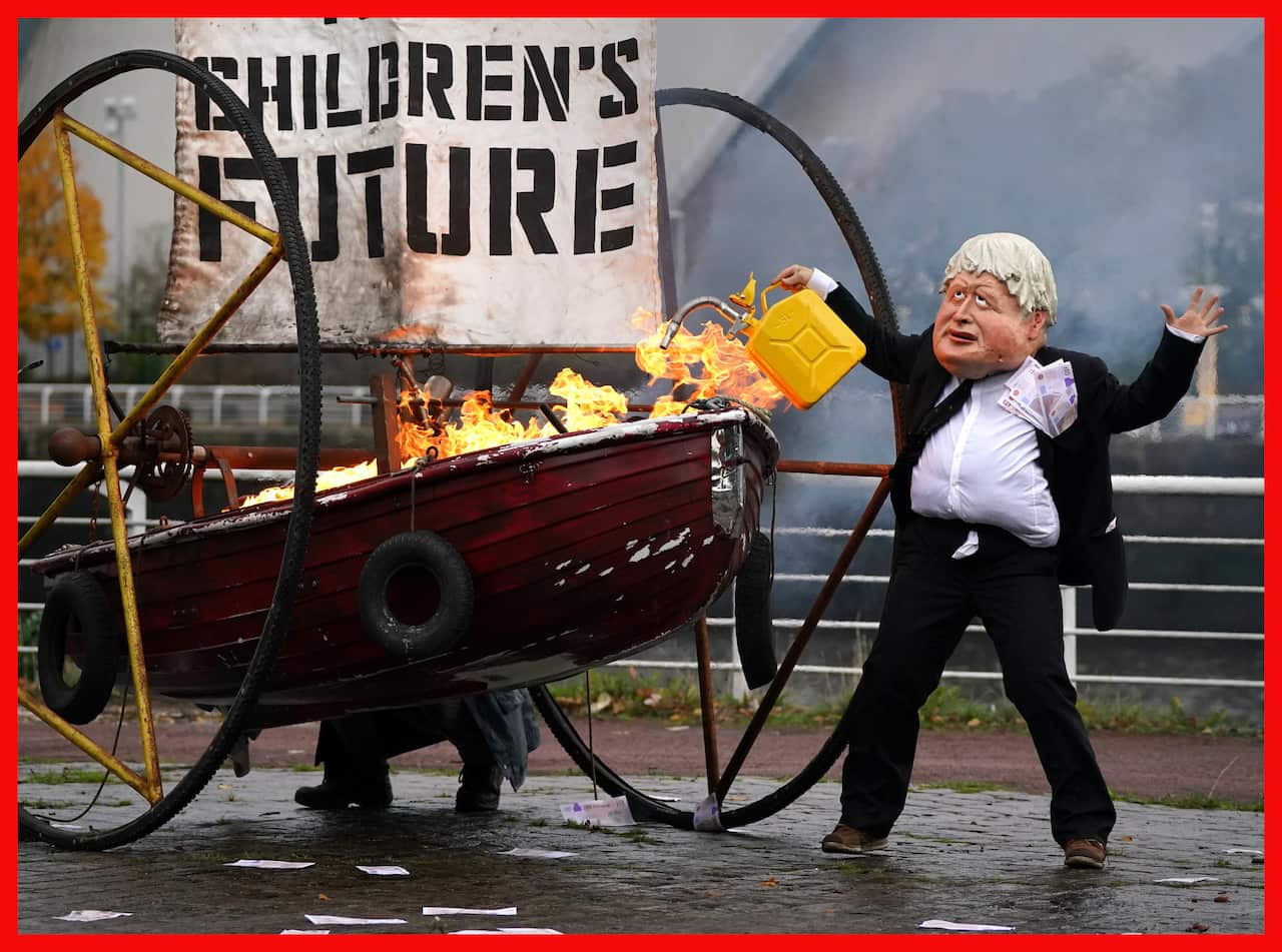 PABest Performers from Ocean Rebellion dressed as Prime Minister Boris Johnson and an Oilhead set light to the sail of a small boat which reads "Your Children's Future" as they burn stacks of money on the banks of the River Clyde in Glasgowm close to the