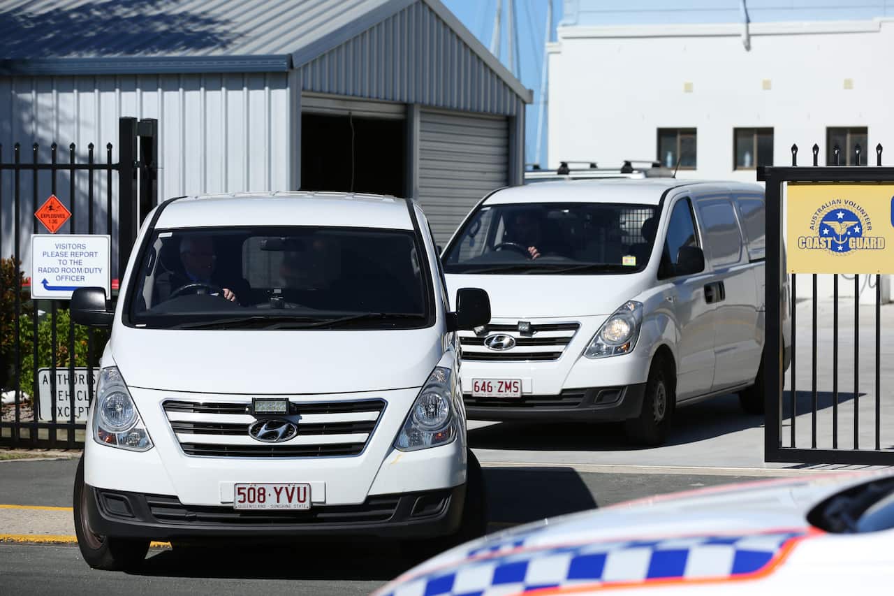 Vans belonging to a funeral home are seen departing the Redcliffe Coast Guard at the Scarborough Marina after a plane crashed into nearby waters, north of  Brisbane, Sunday, December 19, 2021. Queensland Police have confirmed two adults and two children h