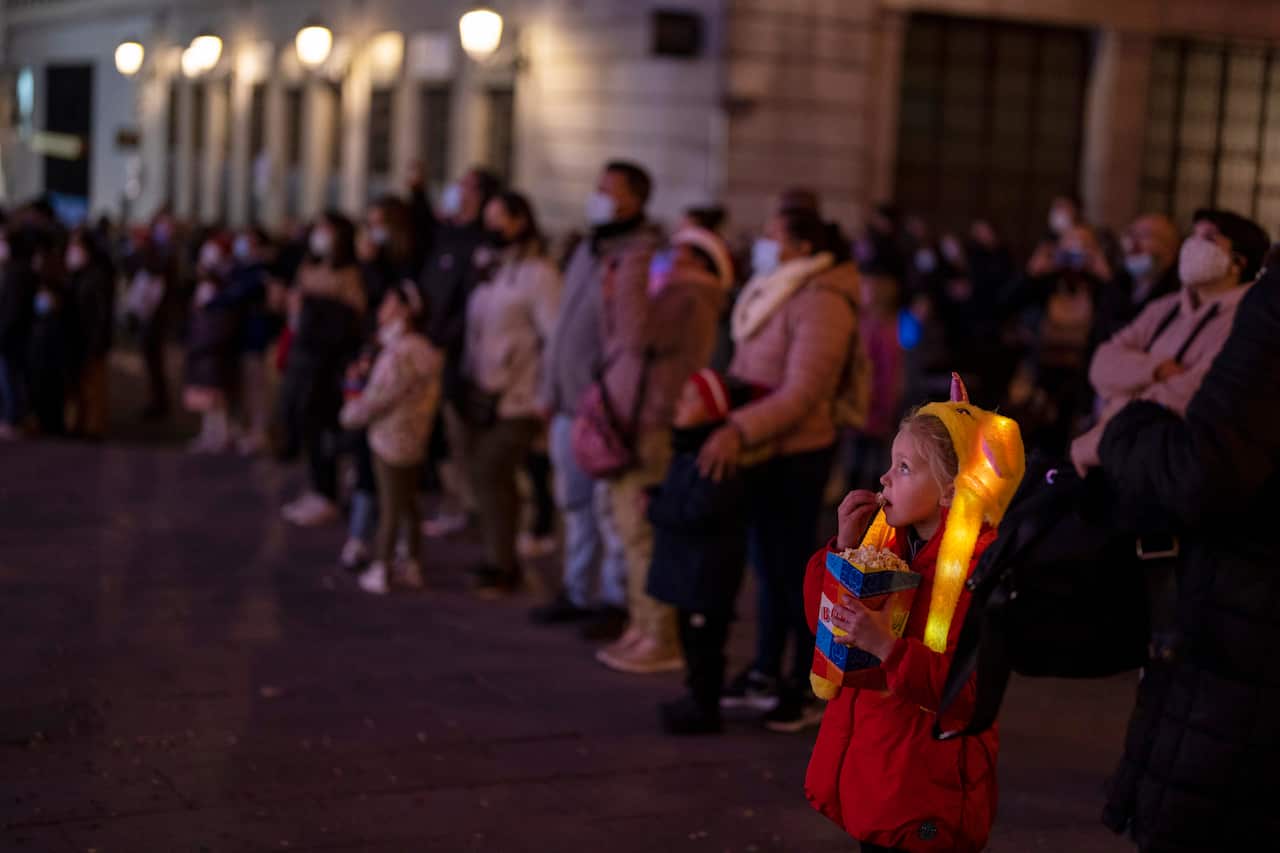 A kid enjoys christmas show in downtown Madrid, Spain, Wednesday, Dec. 22, 2021. Spanish Prime Minister Pedro Sanchez is convening a special Cabinet meeting Thursday to pass a decree-law that makes it mandatory to wear masks outdoors, amid a record surge 