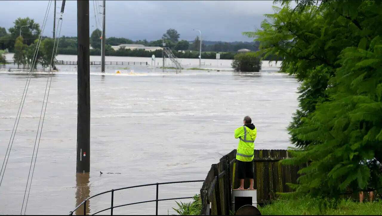 Residents watch over their fence as floodwater rises from the Hawkesbury river at Windsor, north west of Sydney, 3 March, 2022.