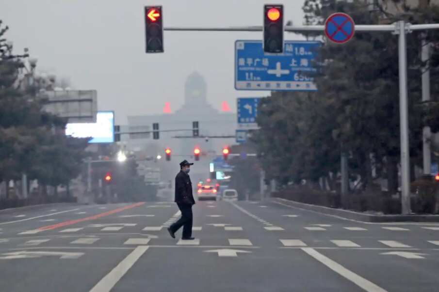 A man walks across an empty road during the fourth day of a city-wide lockdown in Changchun in northeastern China's Jilin province on Monday