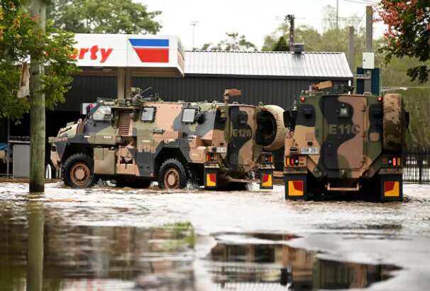 Army vehicles are seen driving through floodwater on March 31, 2022, in Lismore, NSW. 