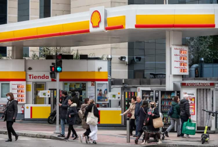 Pedestrians walk past the Global group of energy and petrochemical companies, Shell Oil Company, gas and oil station in Spain.