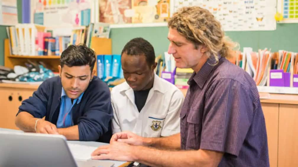 A high school teacher helping students in a classroom