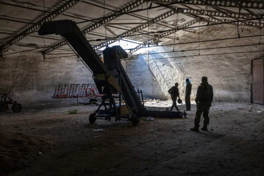 Local government officials and a Ukrainian soldier inspect a grain warehouse shelled by Russian forces near the frontlines of Kherson , Ukraine