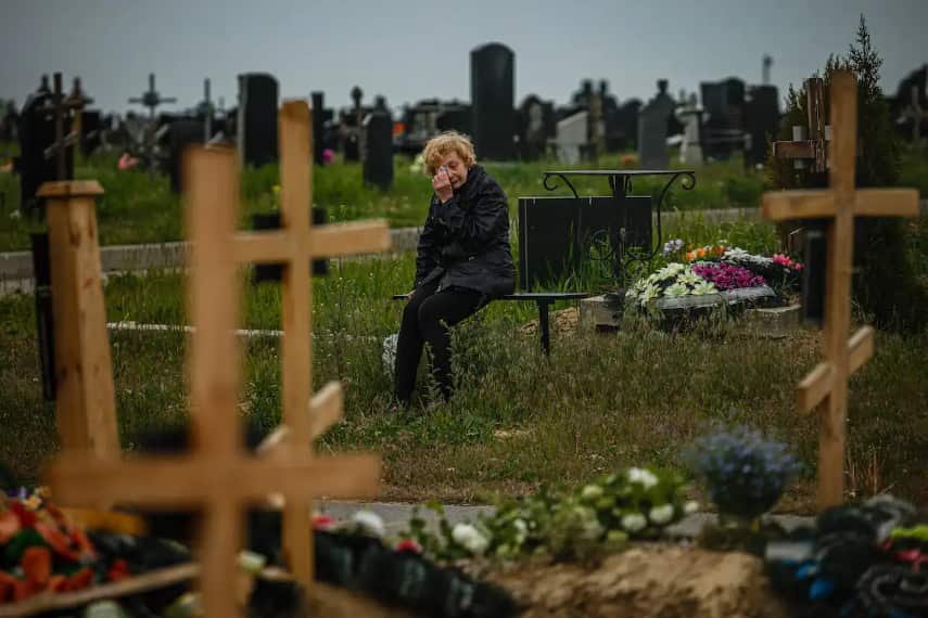 A woman mourns while visiting the grave of Stanislav Hvostov, 22, a Ukrainian serviceman killed during the Russian invasion of Ukraine, in the Kharkiv cemetery.