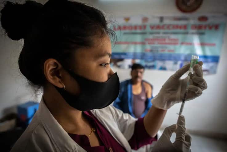 A nurse prepares to give a COVID vaccine to a man at a clinic in India.