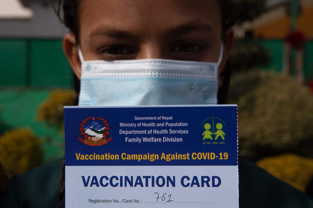 A young child shows her vaccination card after receiving a shot of Moderna Covid-19 vaccine at Marigold School in Bhaktapur, Nepal, 10 January 2022.