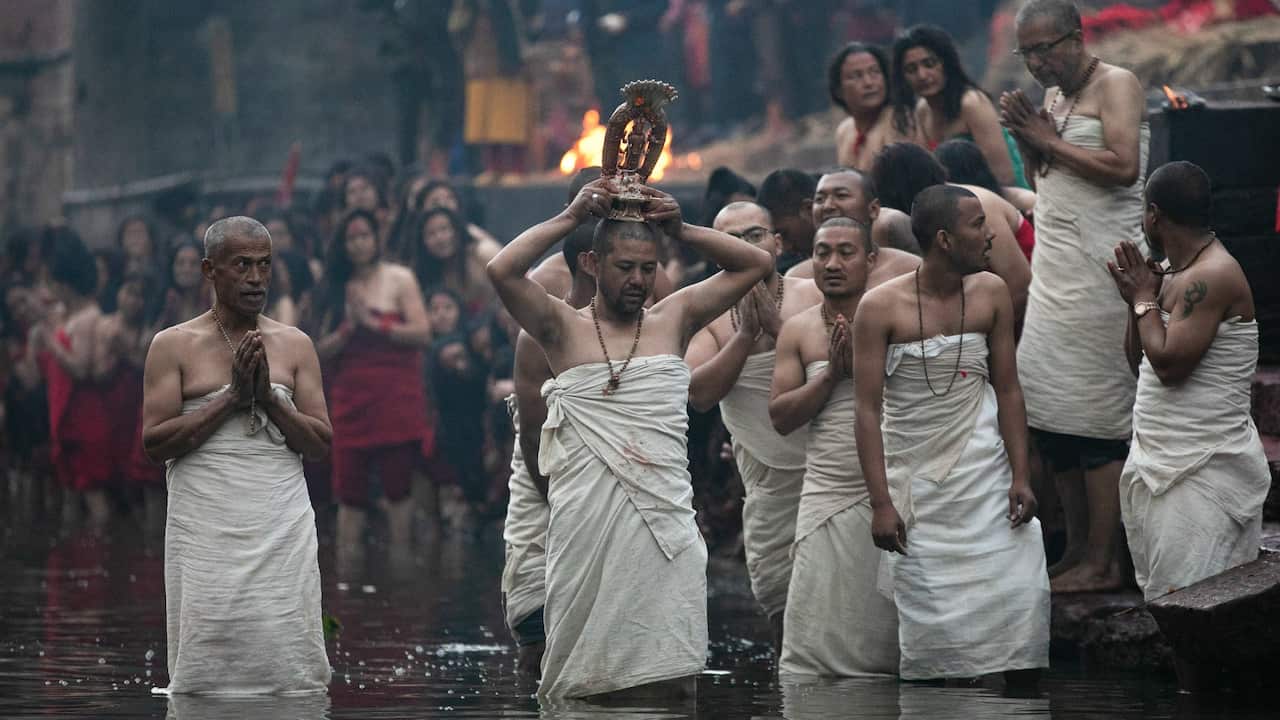 Nepali Hindu devotee baths the idol Madhav Narayan in the Bagmati river during the Swasthani Brata Katha festival.