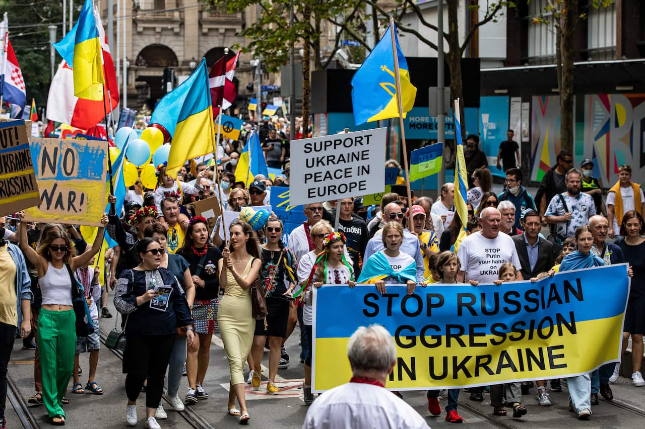 Protesters hold placards and flags during a rally against the war in Ukrainein Melbourne, Sunday, February 27, 2022. Ukrainian Australians want more action from the federal government after Russian President Vladimir Putin launched a military invasion in 