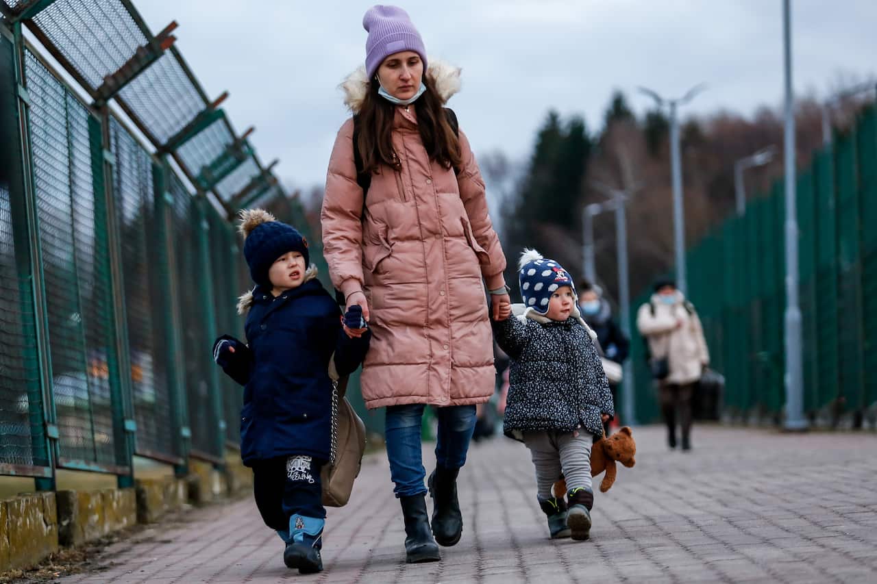 Ukrainian family walks through border passage as tens of thousands escapees from Ukraine enter Poland after Russia takes more Ukrainian territory - Polish-Ukrainian border crossing in Medyka, Poland on February 25, 2022. As the RussianFederation army cros