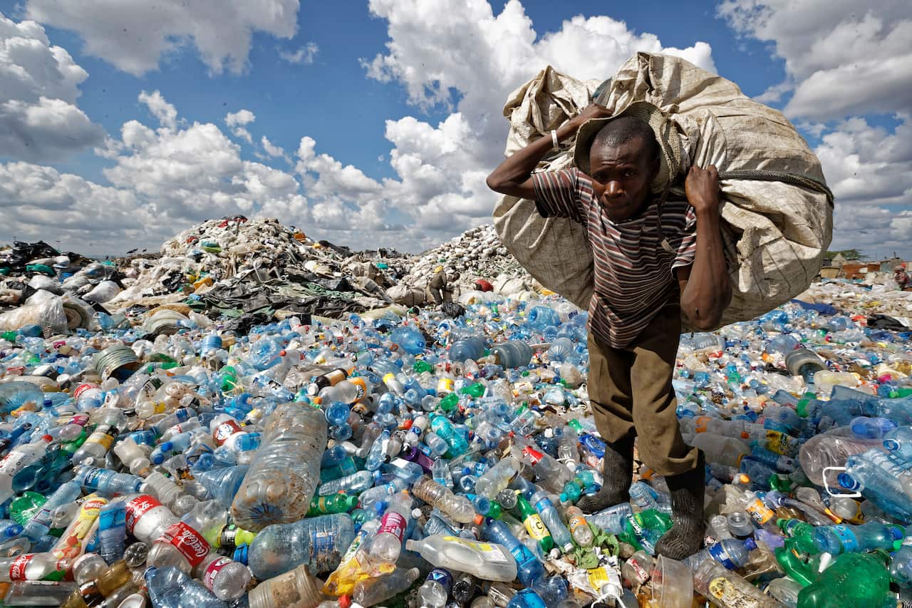 Un uomo raccoglie del materiale riciclabile in una montagna di rifiuti a Nairobi, in Kenya