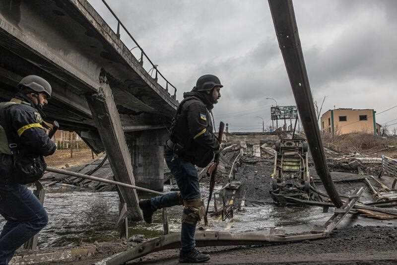 Ukrainian military members walk on a bridge destroyed by shelling in Irpin city, Ukraine, 